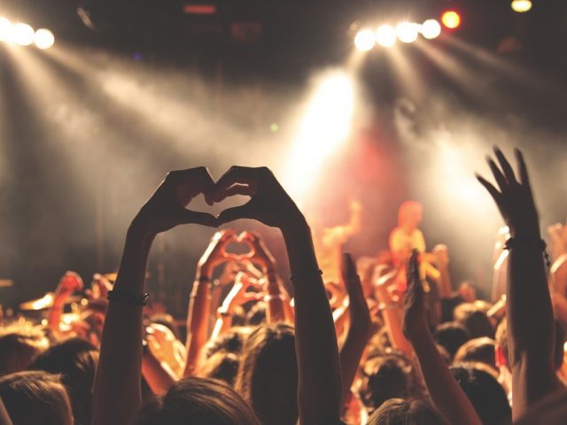 Ett folkhav på en konsert med händer som sträcks upp i formen av ett hjärta.
