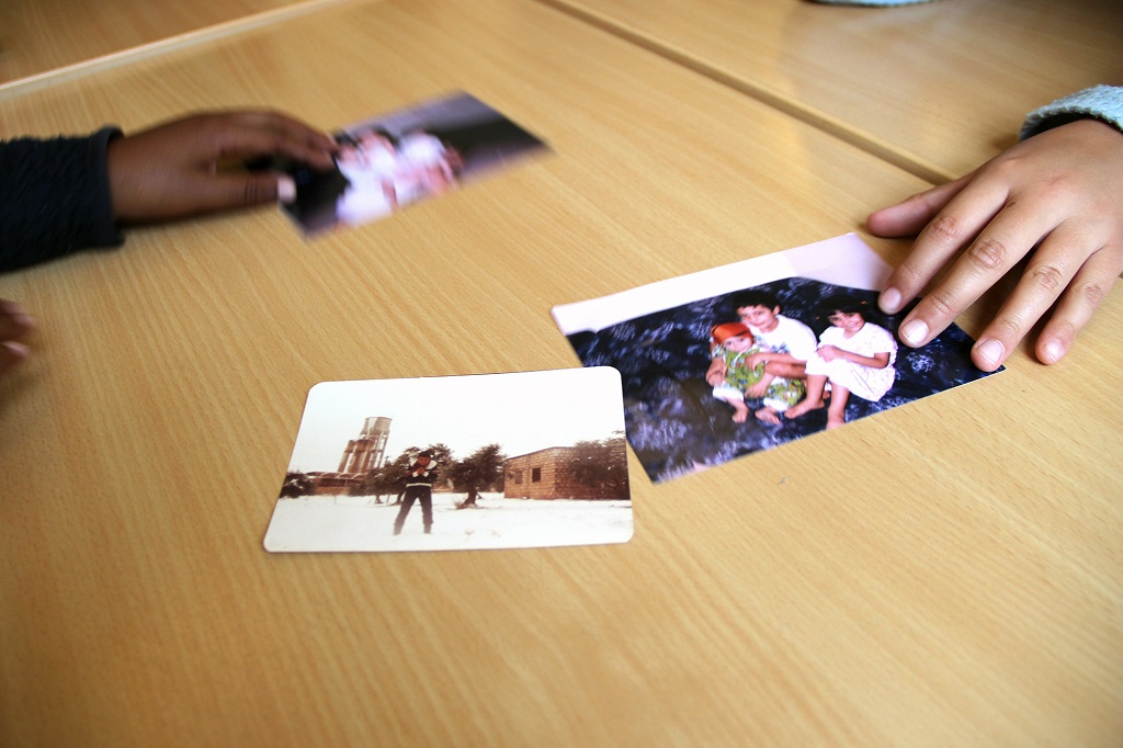 Händer som lägger fram tre fotografier på barn på bordet