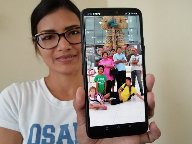 Kvinna visar bild på familjen på mobilen.