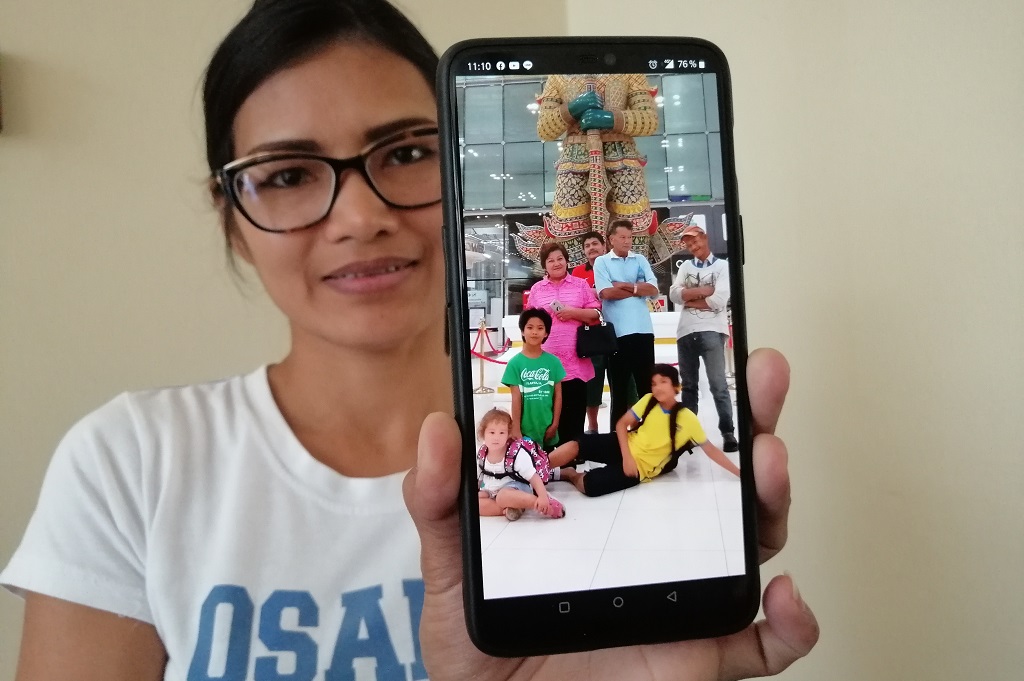 Kvinna visar bild på familjen på mobilen
